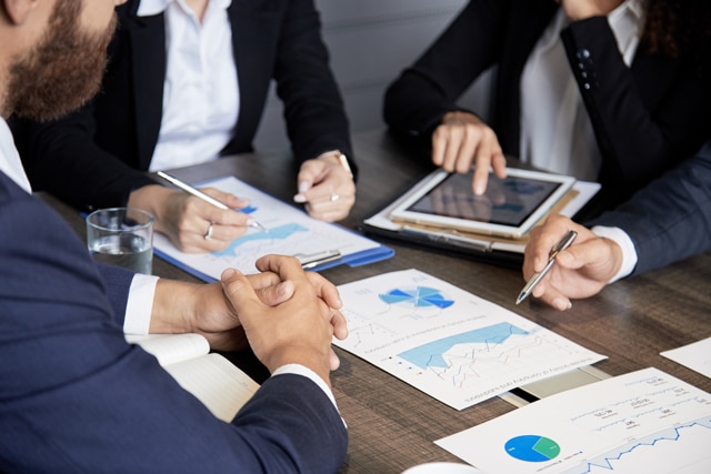 Beratungsgespräch am Besprechungstisch: Auswertungen und Diagramme auf Papier und Tablet